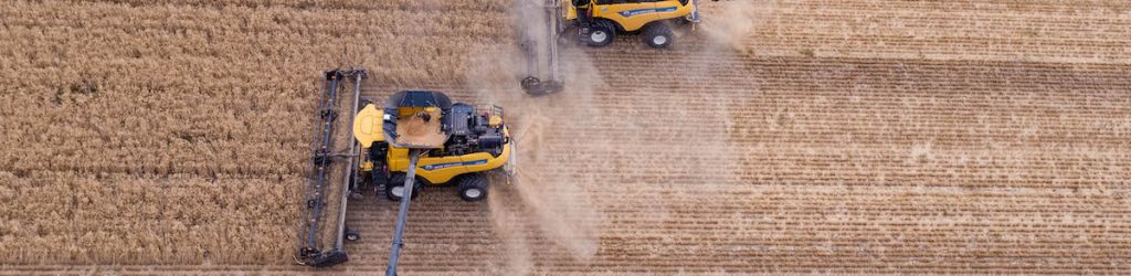 New Holland Harvesters in field grain wheat with John Deere Chaser Horizontal 1200px